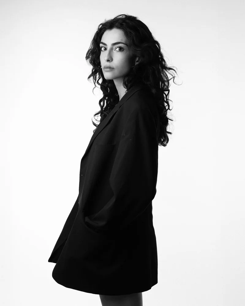 Elvin Köse, black and white studio portrait in a black blazer, side view