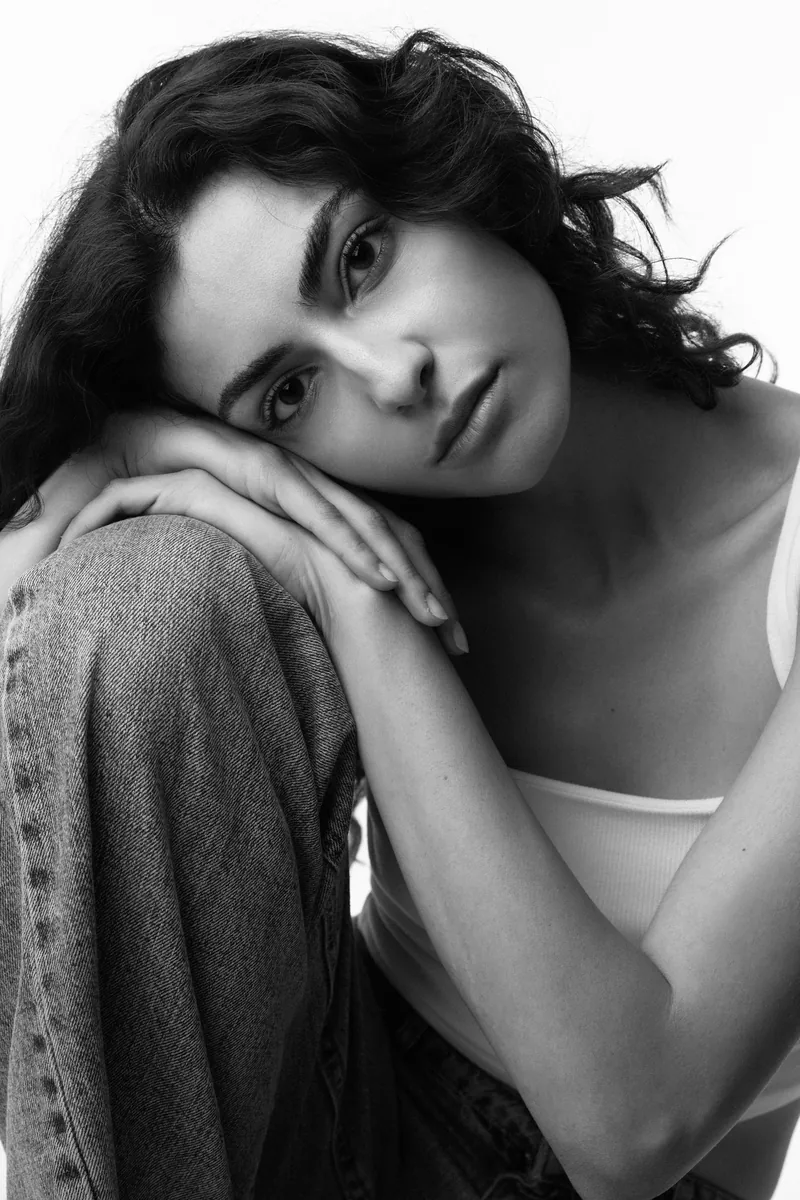 Elvin Köse, black and white studio portrait, head resting on her knee